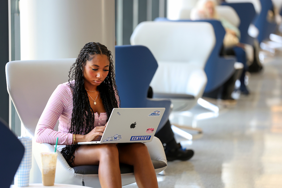 student sitting in students center working on something on their computer.