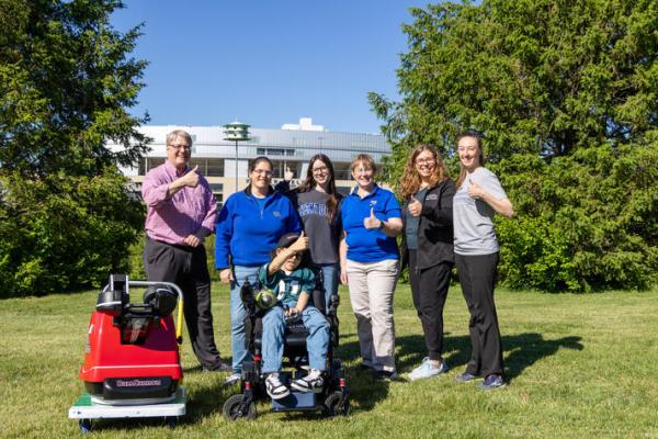 Sam Roberts with members of his care team and UK College of Engineering student Audra Proffitt, who helped design his custom football-throwing device.