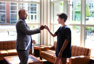 A student fist bumps their advisor in the lobby of the Lewis Honors College.