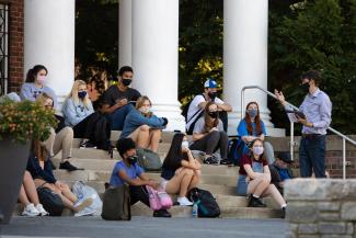 A class meets outside on the steps of Memorial Hall.