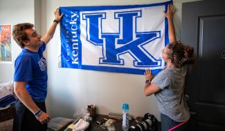 Student hanging up flag in residence hall room