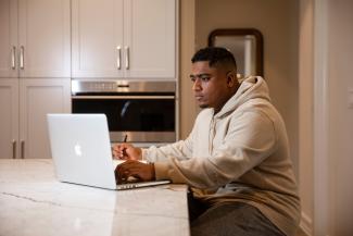 A student works on a laptop at home.