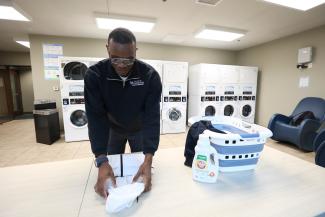 Student folding clothes in dorm laundry room.
