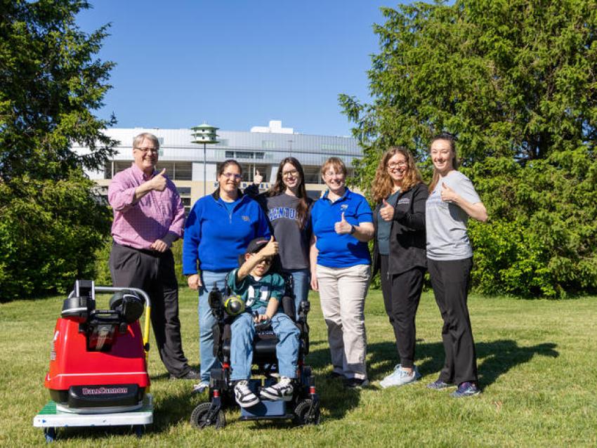 Sam Roberts with members of his care team and UK College of Engineering student Audra Proffitt, who helped design his custom football-throwing device.