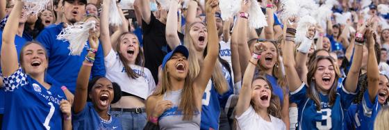 Fans cheering at football game with white pom poms