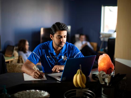 A male student works on a laptop while at home.
