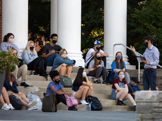 A class meets outside on the steps of Memorial Hall.