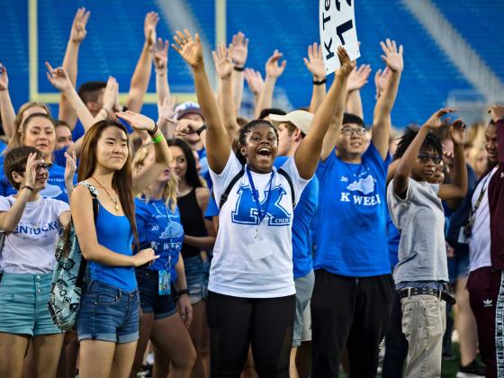 Students wearing UK clothing in a UK stadium cheering