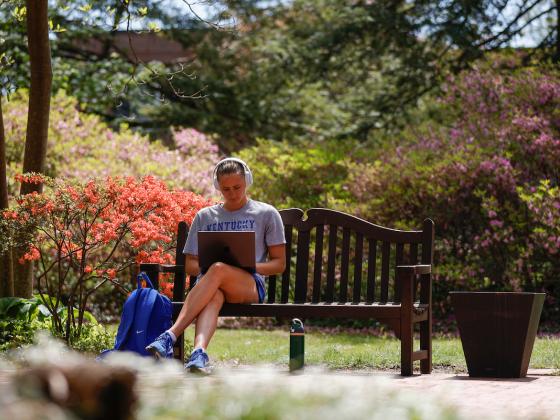 female student sitting on campus working on a laptop